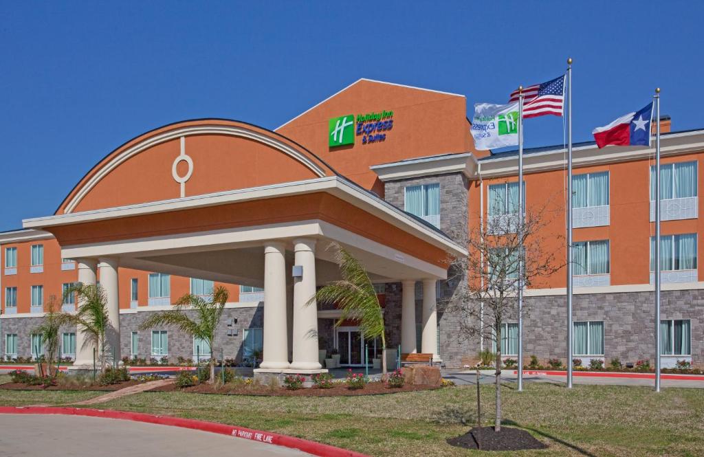 un edificio de oficinas con dos banderas delante en Holiday Inn Express Hotel & Suites Clute-Lake Jackson, an IHG Hotel, en Clute