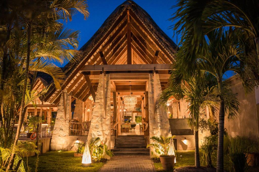 a house with palm trees in front of it at Les Lauriers Eco Hotel in Anse Volbert Village
