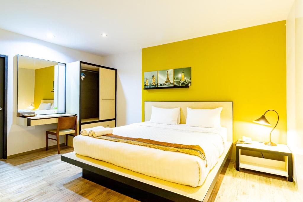 um quarto com uma cama grande e uma parede amarela em Thongmanee Hotel em Hat Yai