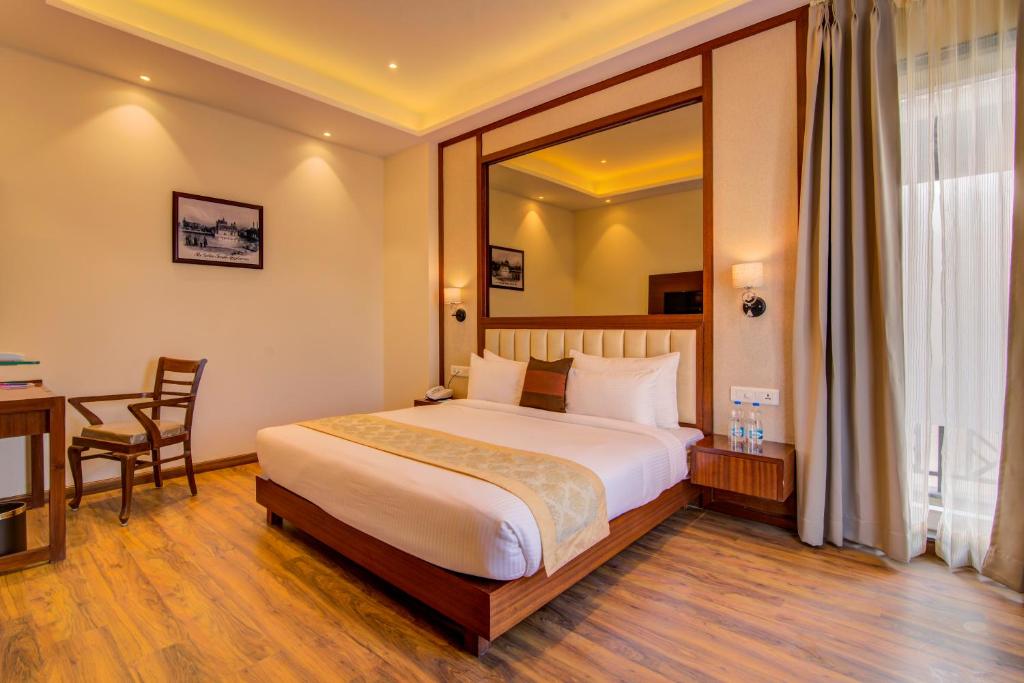 um quarto de hotel com uma cama, uma secretária e uma janela em Amritara Sadka Amritsar em Amritsar