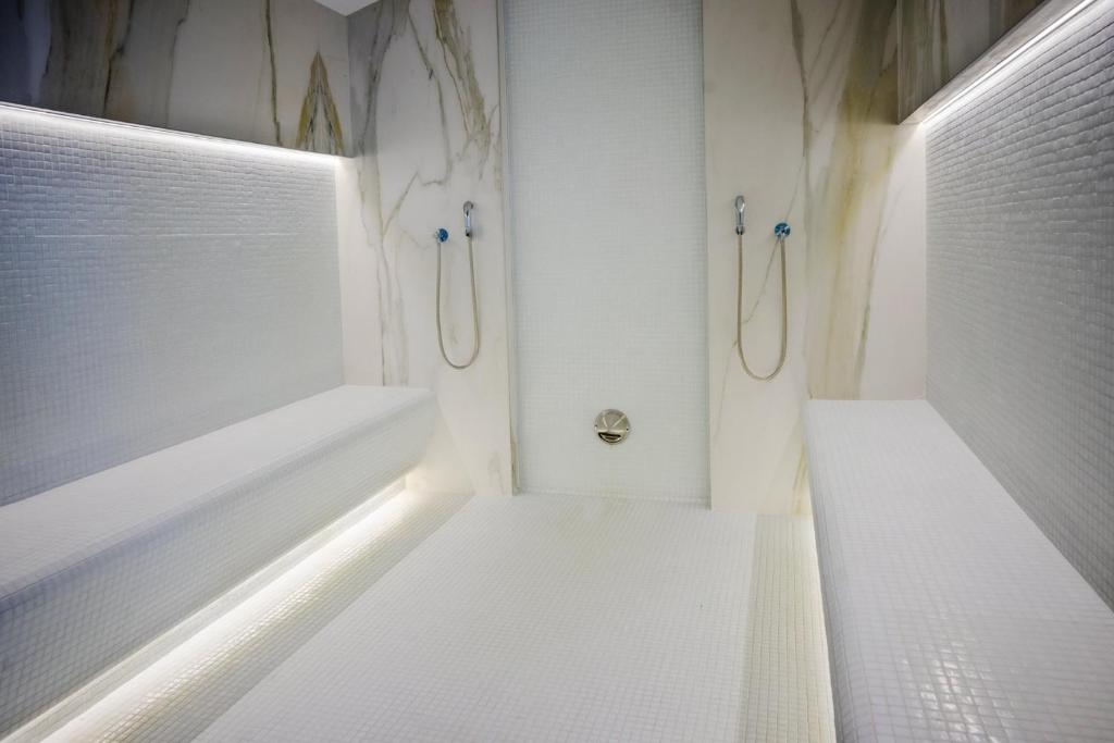 La salle de bains blanche est pourvue d'une baignoire et d'une douche. dans l'établissement Apartament Adrian-Beach Resort, à Mamaia Nord – Năvodari