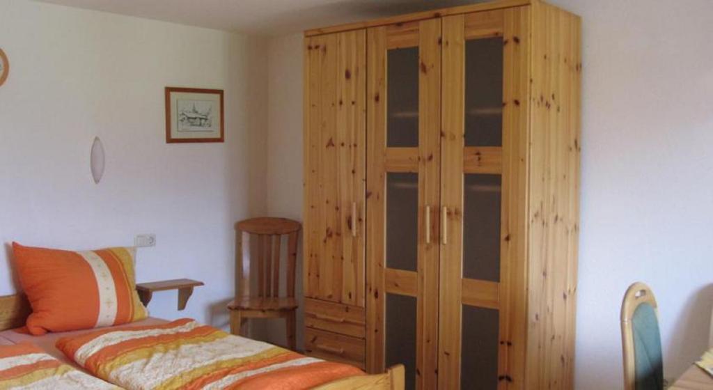 a bedroom with a wooden cabinet next to a bed at Sägerhof Bader in Rettenberg