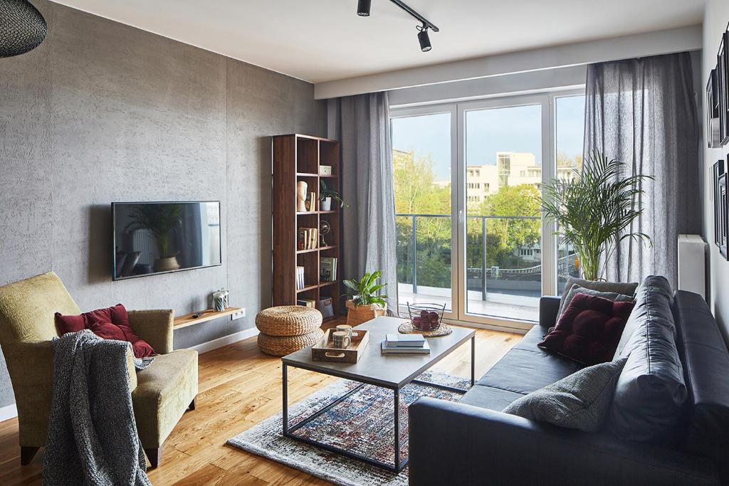 ein Wohnzimmer mit einem Sofa und einem Tisch in der Unterkunft Apartament Żoliborz Arkadia by Renters Prestige in Warschau