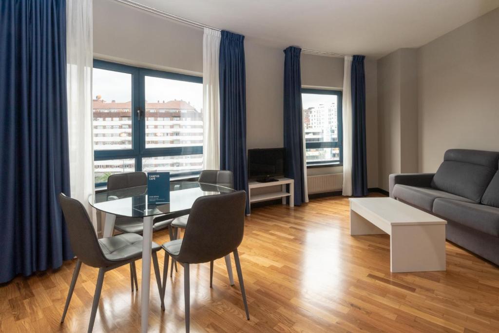 - un salon avec une table, des chaises et un canapé dans l'établissement Aparthotel Campus, à Oviedo