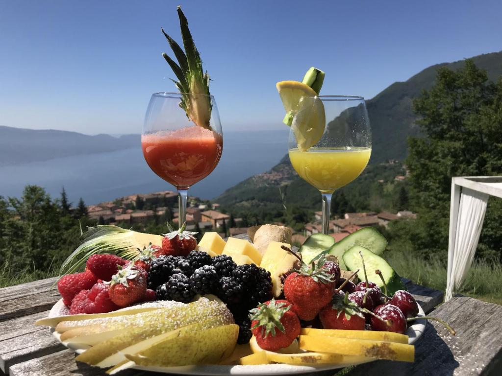 une assiette de fruits sur une table avec deux verres à vin dans l'établissement BnB Borgo le Vigne - La Vendemmia, à Tignale