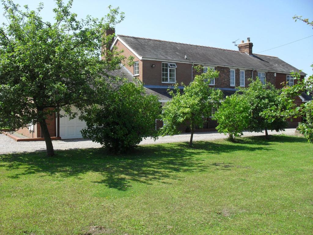 a house with trees in front of a yard at Fernlea Cottage Bed and Breakfast in Tattenhall