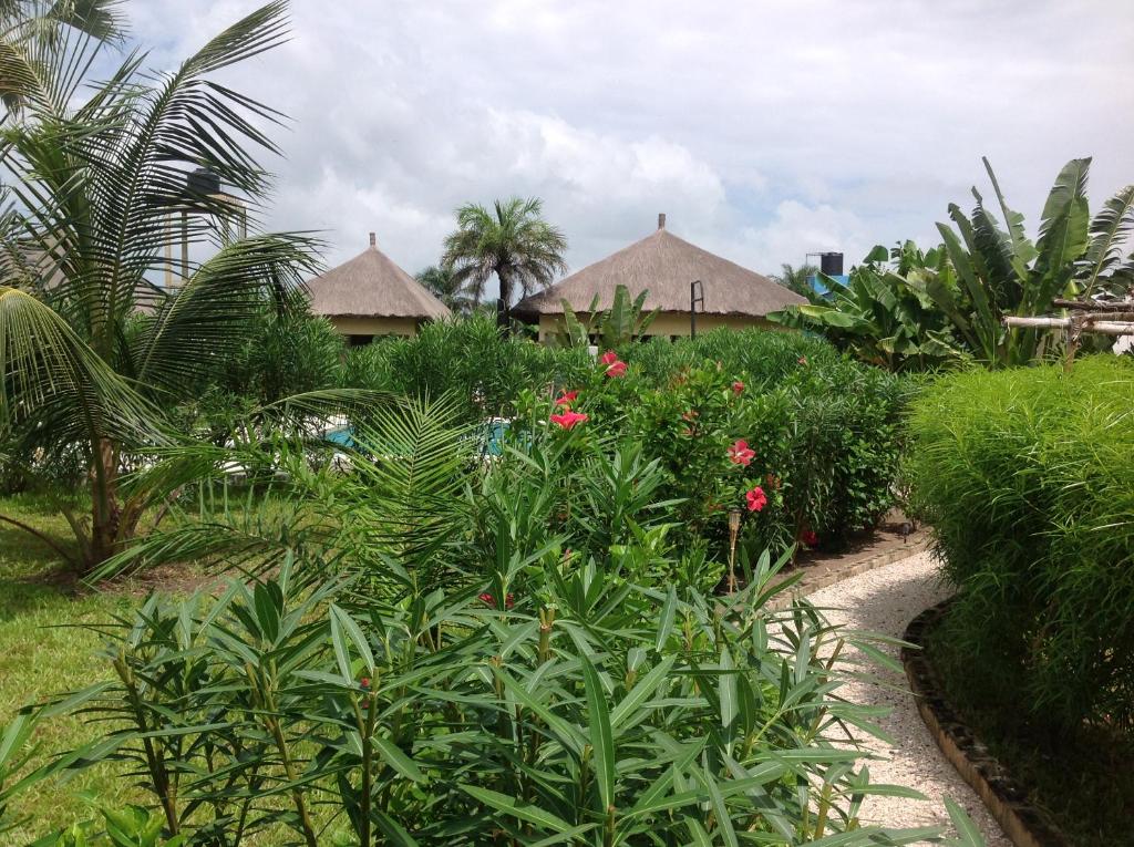 einen Garten mit Blumen und Häusern im Hintergrund in der Unterkunft PACOTOUTY LODGE in Cap Skirring