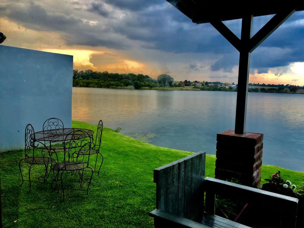 une table et des chaises à côté d'une masse d'eau dans l'établissement Loch Athlone Overnight Accommodation, à Bethlehem