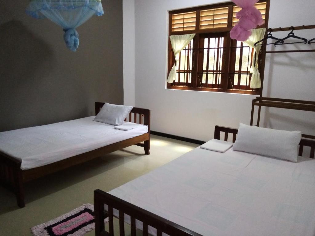 a room with two beds and a window at Sunny Side 89 in Galle