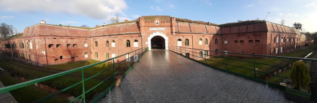 ein großes rotes Backsteingebäude mit einer Brücke davor in der Unterkunft Twierdza Toruń - Fort IV in Toruń