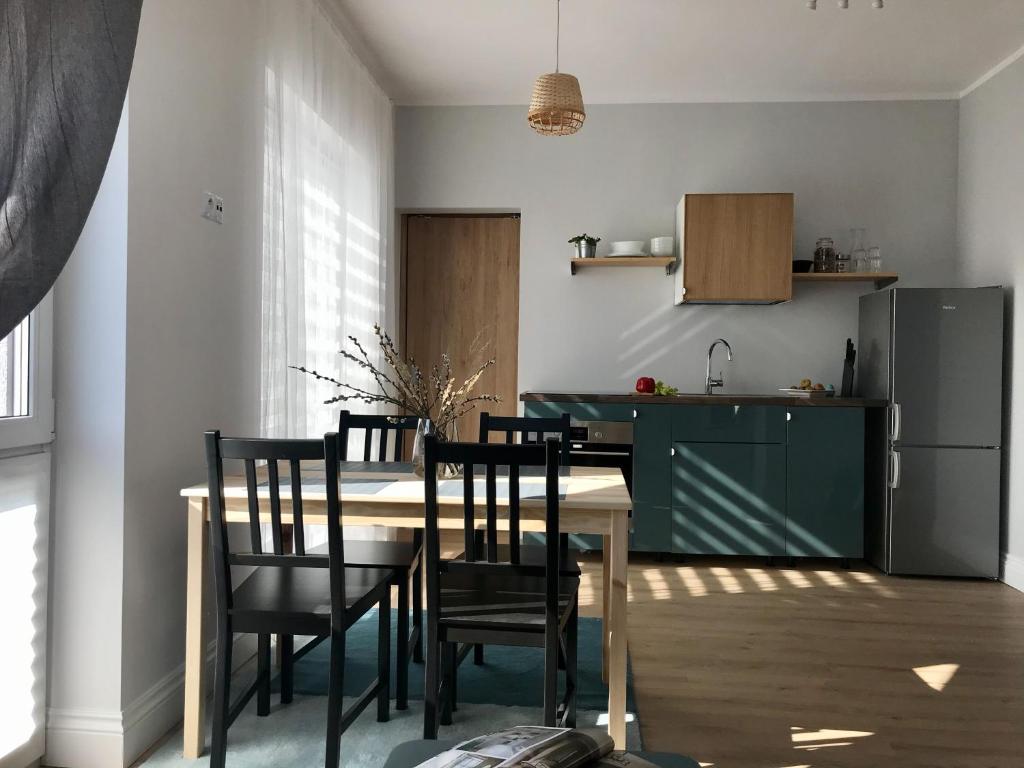 a kitchen with a table and chairs and a refrigerator at Zastava Apartamenty in Włoszczowa