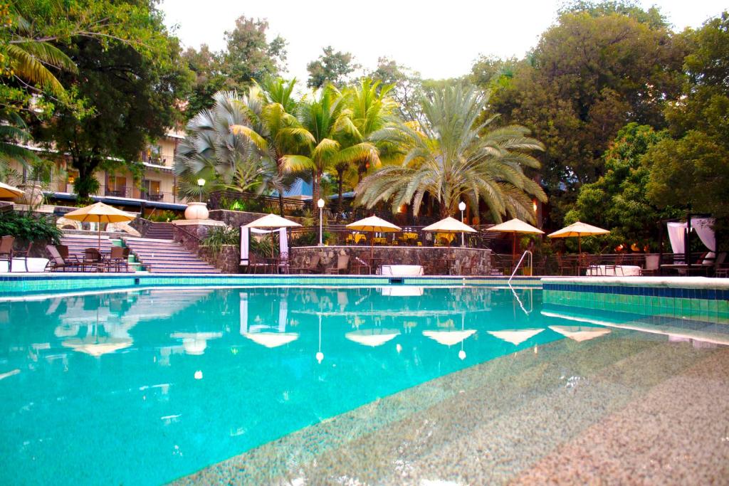 a pool with chairs and umbrellas in the middle of it at Karibe Hotel in Port-au-Prince