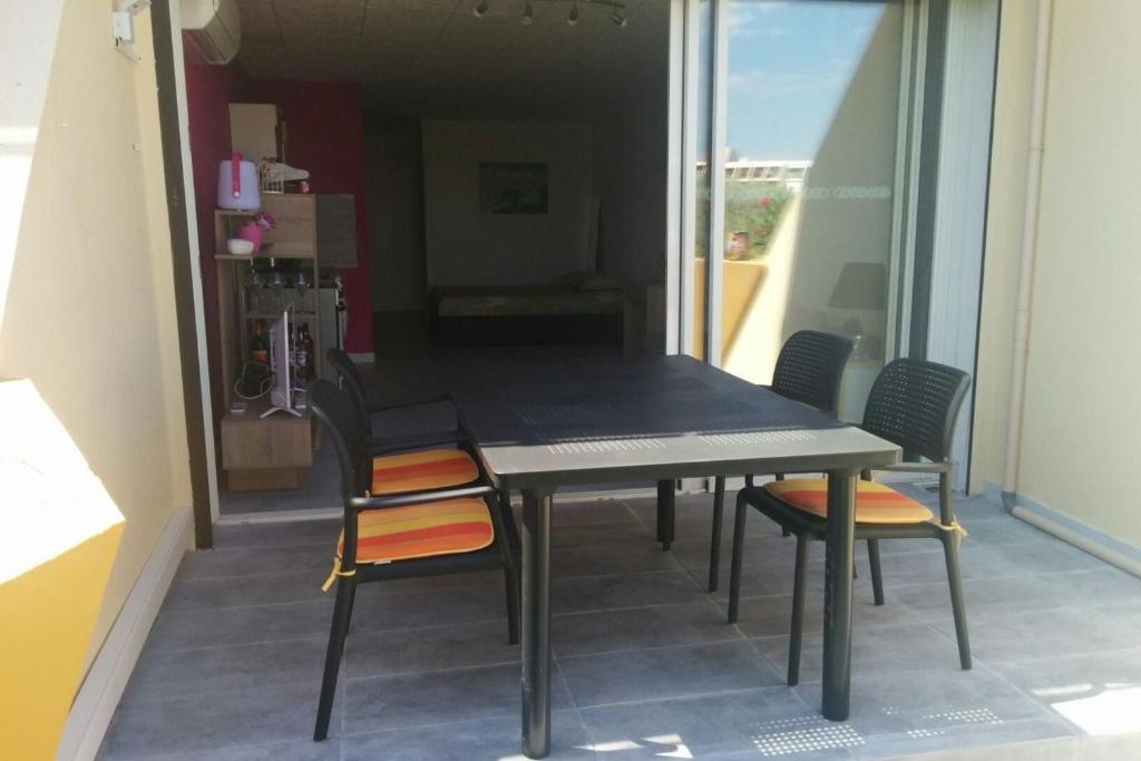une table et des chaises dans une pièce avec une fenêtre dans l'établissement Naturiste Cap d'Agde Héliopolis C 77, au Cap d'Agde