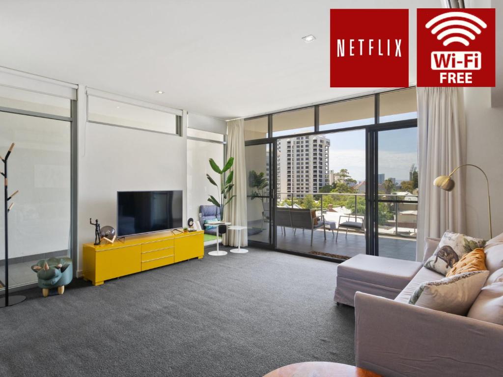 a living room with a tv and a yellow cabinet at 2bdrm Skyline Views - Prime for River, WACA, OPTUS Stadium in Perth
