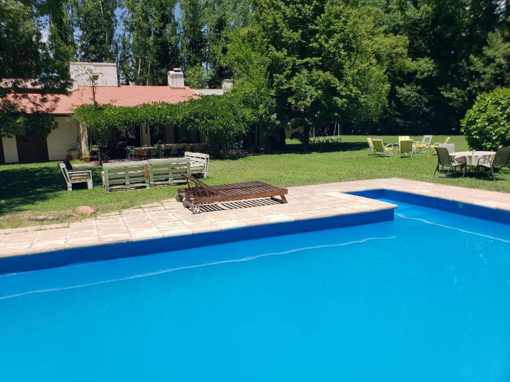 a blue swimming pool with a bench and a house at Casa Vistalba 220 dolarblue B La Capilla in Ciudad Lujan de Cuyo