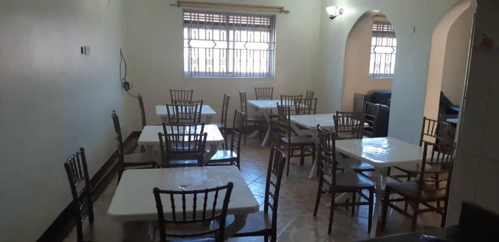 a dining room with tables and chairs and windows at Hotel Dot Com Entebbe in Entebbe