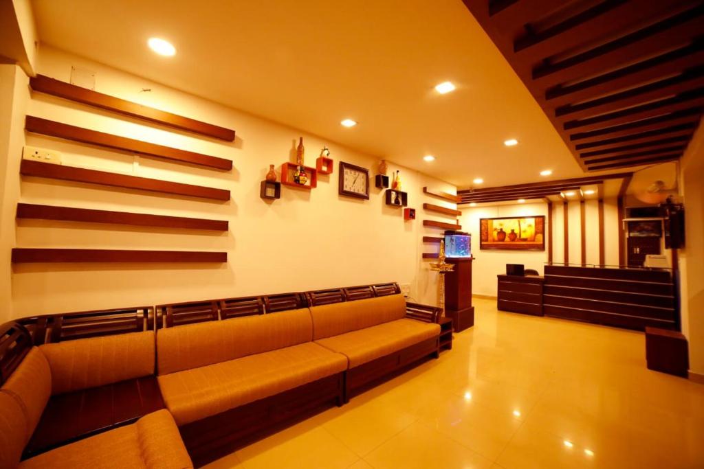 a living room with a couch and a television at Kairali Tourist Home in Guruvāyūr