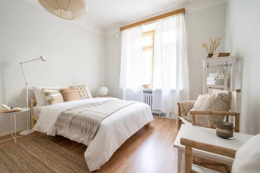 a white bedroom with a bed and a window at Roost Liisankatu in Helsinki
