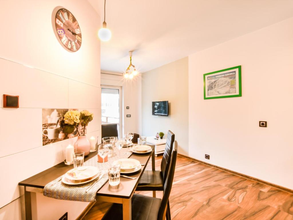 a dining room with a table and chairs and a clock on the wall at VacationClub – Dworcowa 1A Apartament 3 in Szklarska Poręba