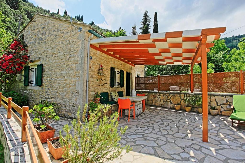 a patio with a table and a wooden pergola at Korinas Cottage: Stone cottage close to the beach in Agní