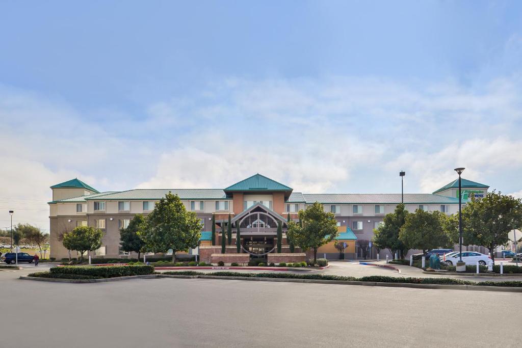 a large building with a parking lot in front of it at HOLIDAY INN EXPRESS & SUITES ELK GROVE CENTRAL - HWY 99, an IHG Hotel in Elk Grove