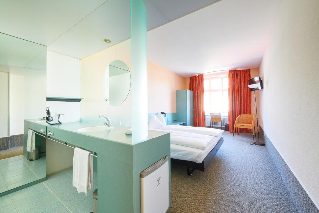 ein Bad mit einem Waschbecken und ein Bett in einem Zimmer in der Unterkunft Hotel City am Bahnhof in Bern