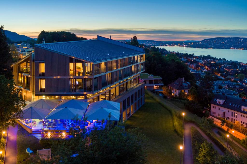 un bâtiment avec des tentes bleues devant lui la nuit dans l'établissement Belvoir Swiss Quality Hotel, à Rüschlikon