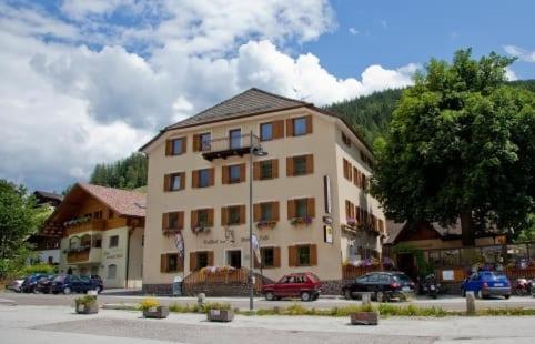 un gran edificio con coches estacionados frente a él en Gasthof Zum Weissen Rössl, en Sarentino