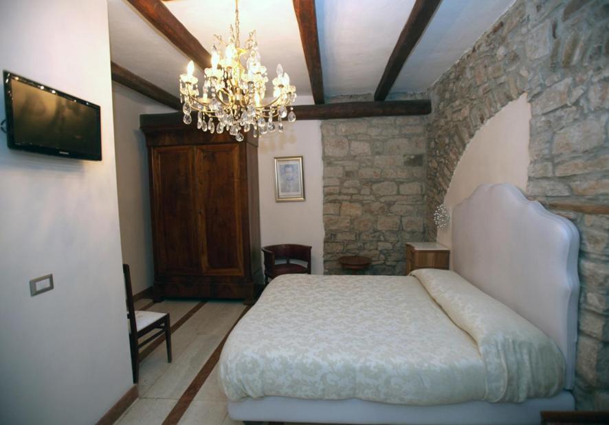 um quarto com uma cama grande e um lustre em La Cantina del Convento em Potenza