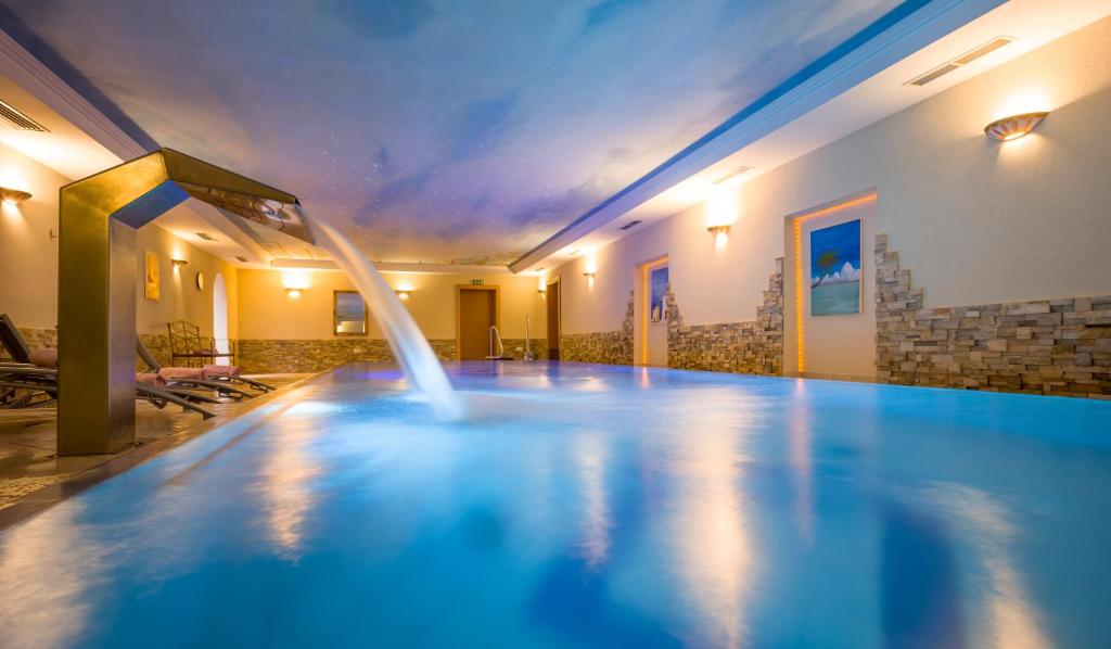 a swimming pool with a fountain in a building at Seetals Wohnwelt in Stumm