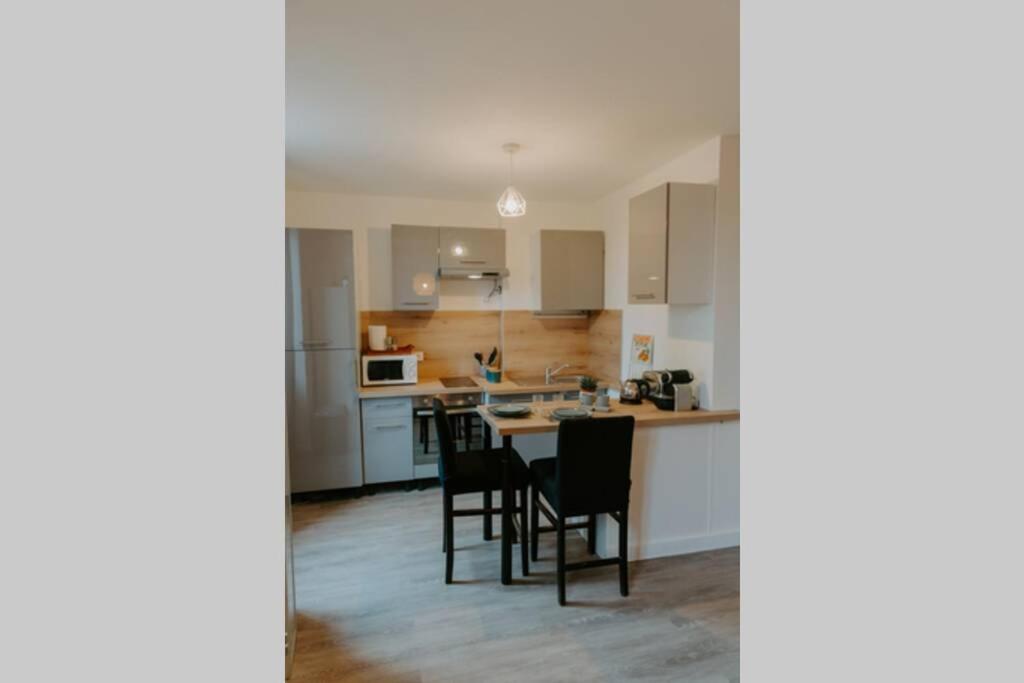 a kitchen with white cabinets and a table and chairs at Les berges du Roubion studio cosy et moderne in Montélimar