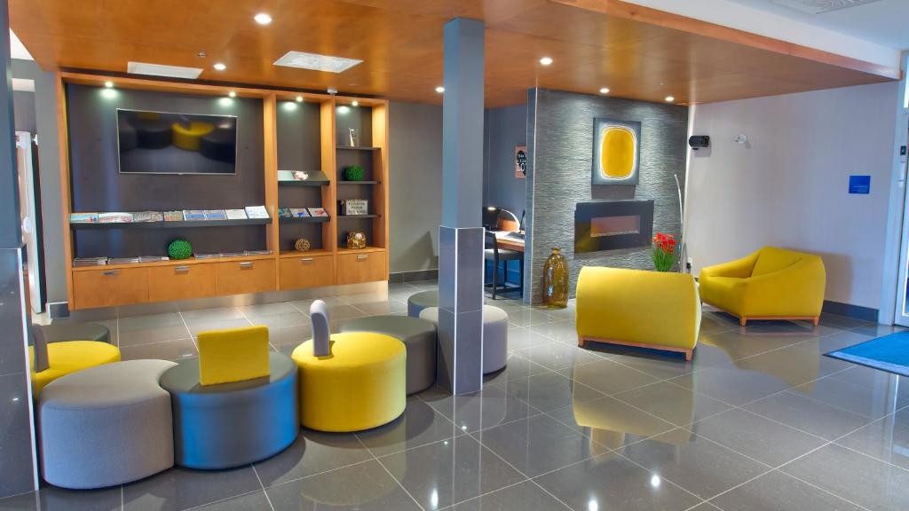 um átrio com cadeiras amarelas e brancas e uma televisão em Holiday Inn Express & Suites Vaudreuil-Dorion, an IHG Hotel em Vaudreuil-Dorion