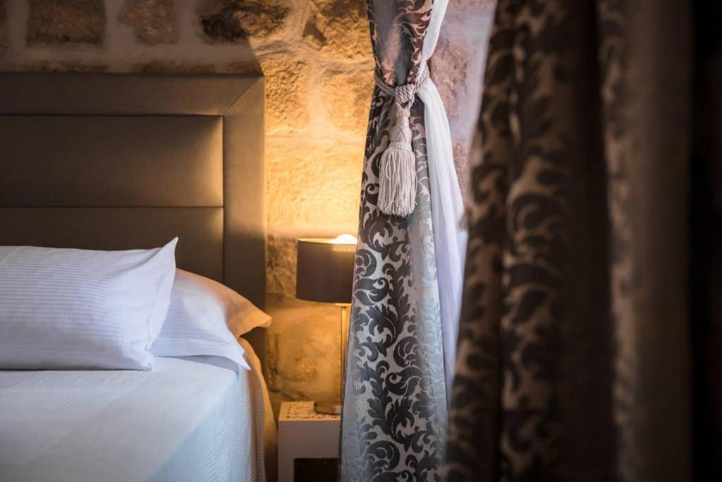 a bedroom with a bed and a curtain and a lamp at The Saint Blaise Luxury Collection in Dubrovnik