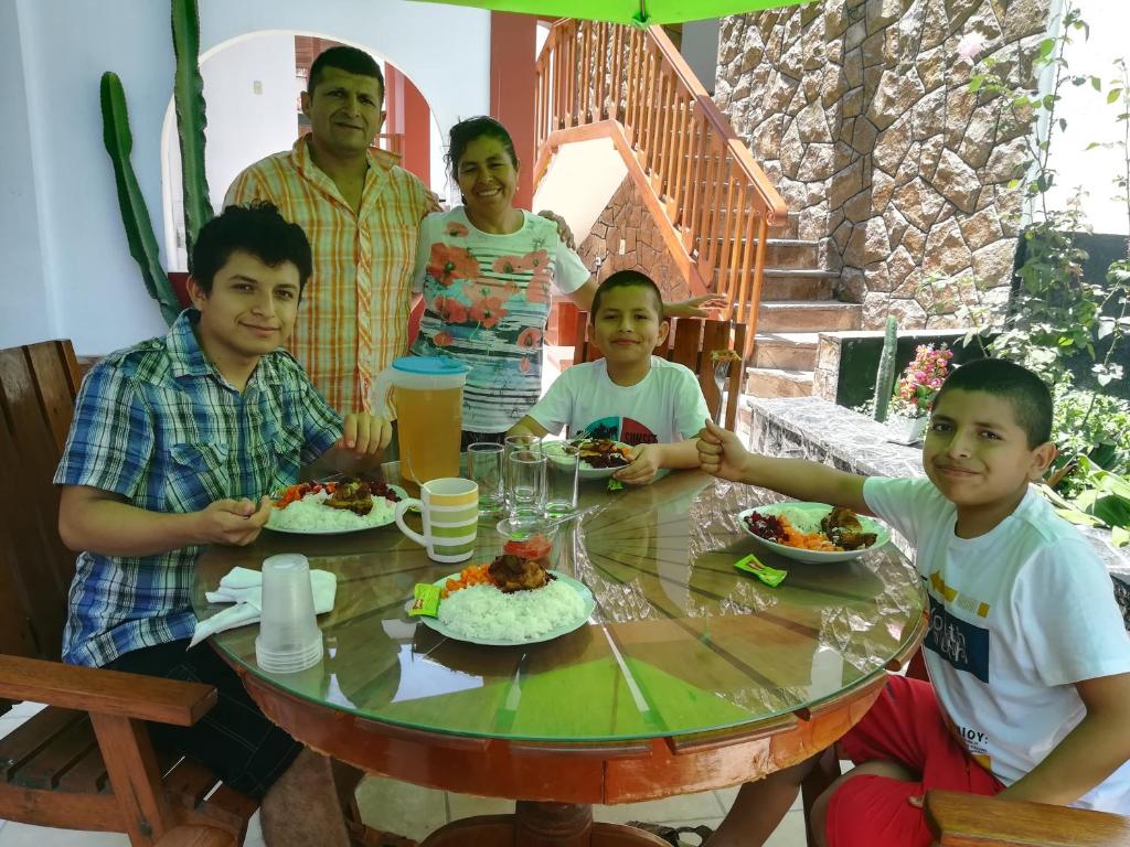 un grupo de personas sentadas alrededor de una mesa comiendo comida en Hospedaje Fremiott en Huanchaco