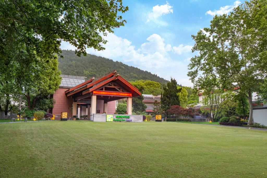 a building with a grass field in front of it at Holiday Inn Resort Chaohu Hot Spring, an IHG Hotel in Chaohu