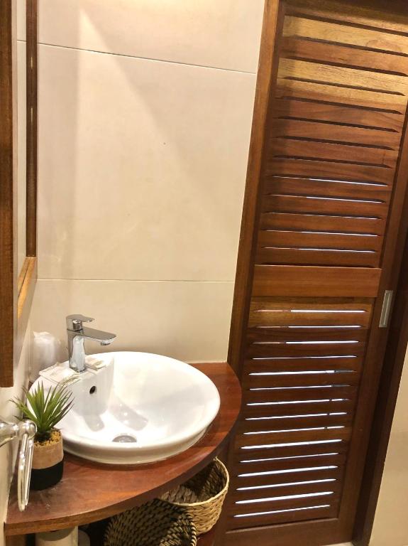 a bathroom with a white sink and a wooden shelf at Centr'Hotel in Marigot