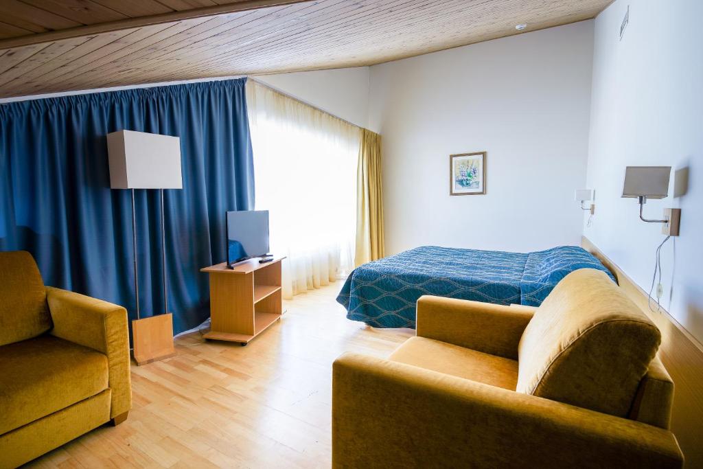 um quarto com uma cama, um sofá e uma cadeira em Fra Mare Thalasso Spa em Haapsalu