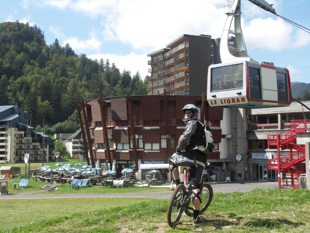 a man riding a bike in front of a ski lift at LE SAPORTA- Studios et Appartements meublés de tourisme in Le Lioran