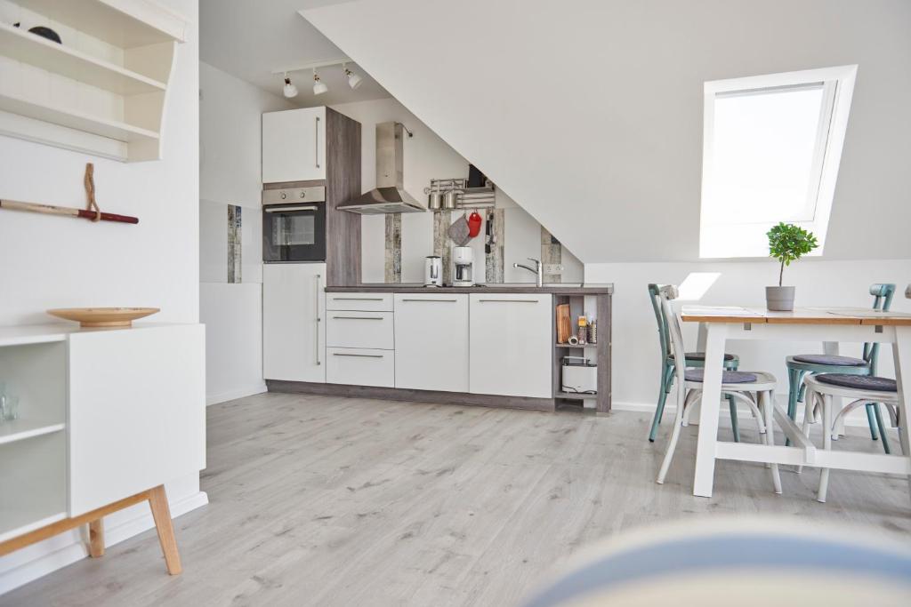 a kitchen with white cabinets and a table with chairs at Liegeplatz Appartements in Fockbek