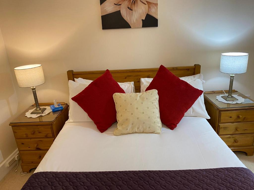 Schlafzimmer mit einem Bett mit roten und weißen Kissen in der Unterkunft Turi House in Canterbury