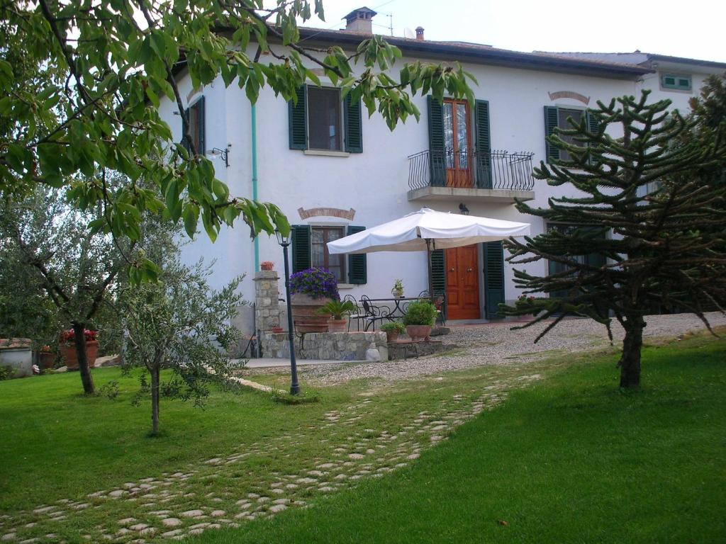 une maison blanche avec un parasol dans une cour dans l'établissement Casa Vacanze Bellavista, à San Casciano in Val di Pesa