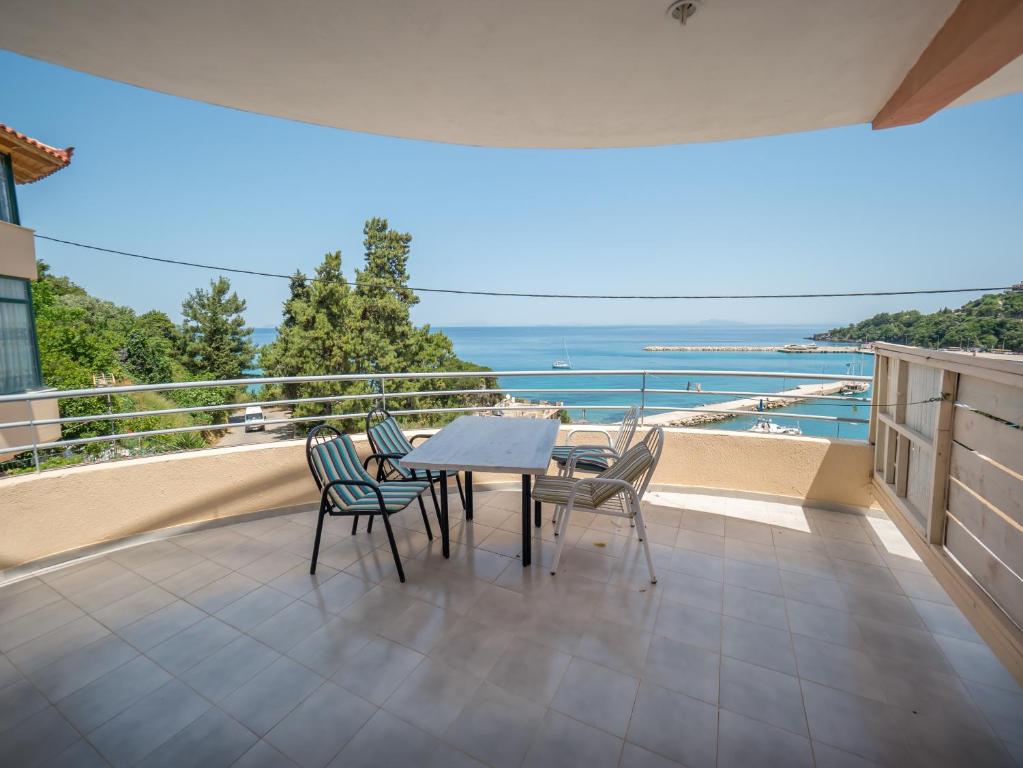 een tafel en stoelen op een balkon met uitzicht op de oceaan bij Harbour View - Oceanis Apartments in Póros