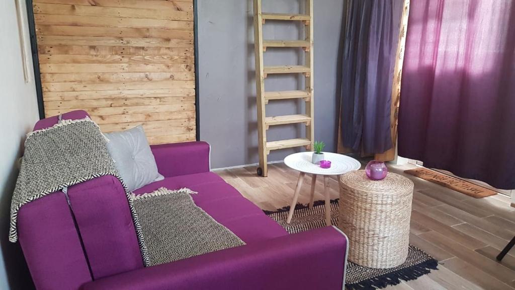uma sala de estar com um sofá roxo e uma mesa em La Tita em Schœlcher