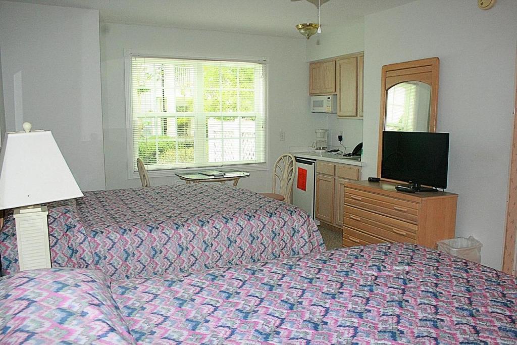 een slaapkamer met 2 bedden, een tv en een keuken bij Brunswick Plantation Golf Home 501L in Calabash