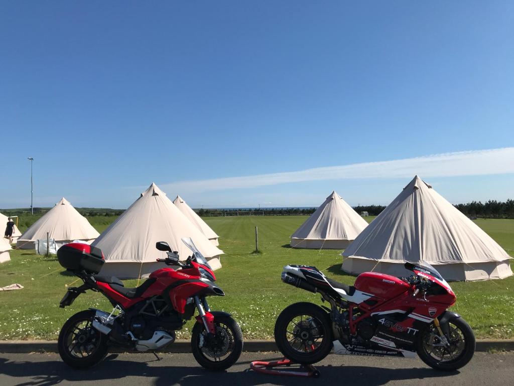 twee motorfietsen geparkeerd voor sommige tenten bij 4Ever TT Glamping in Colby