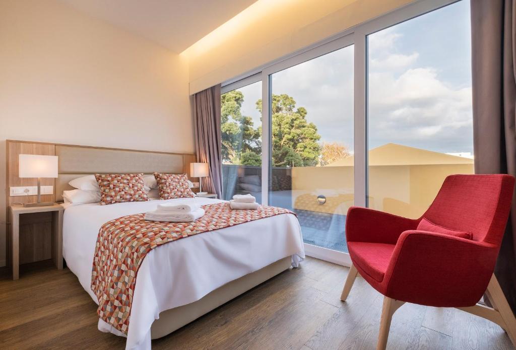 a hotel room with a bed and a red chair at Casas Amarelas Azores in Ponta Delgada