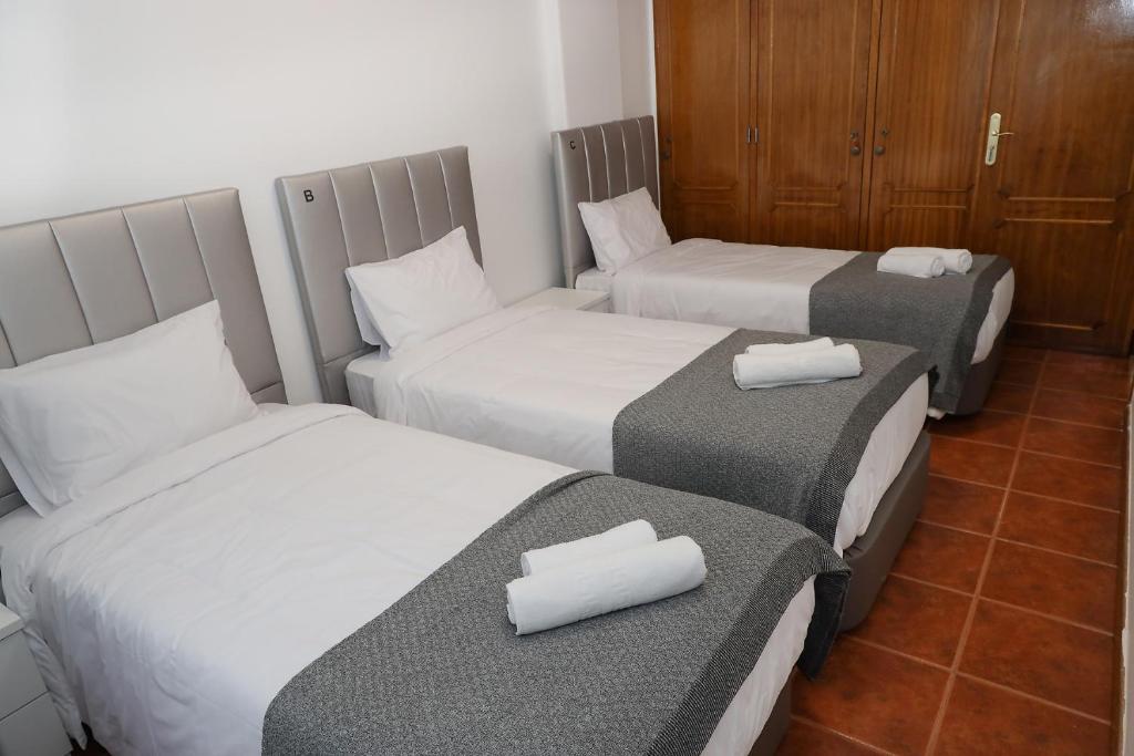 a hotel room with three beds with towels on them at lisbon Home host in Lisbon