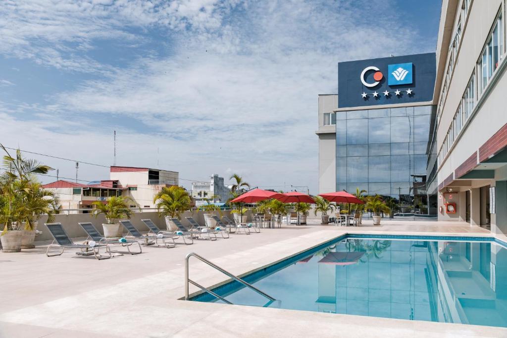 Costa del Sol Wyndham Pucallpa في بوكالبا: مسبح في فندق فيه كراسي ومبنى
