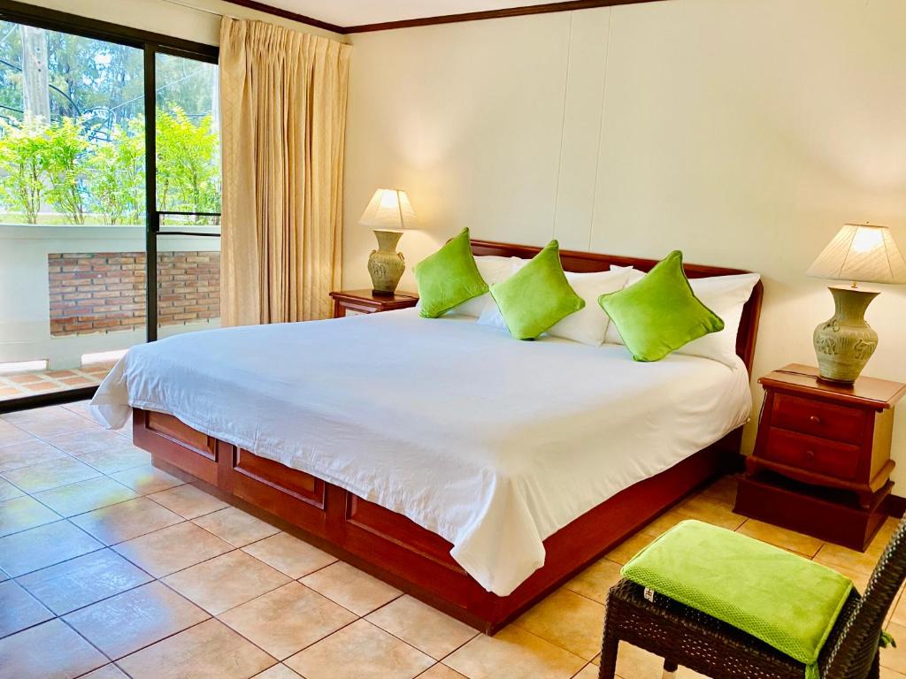 una camera da letto con un grande letto con cuscini verdi di Surin Bay Inn a Surin Beach