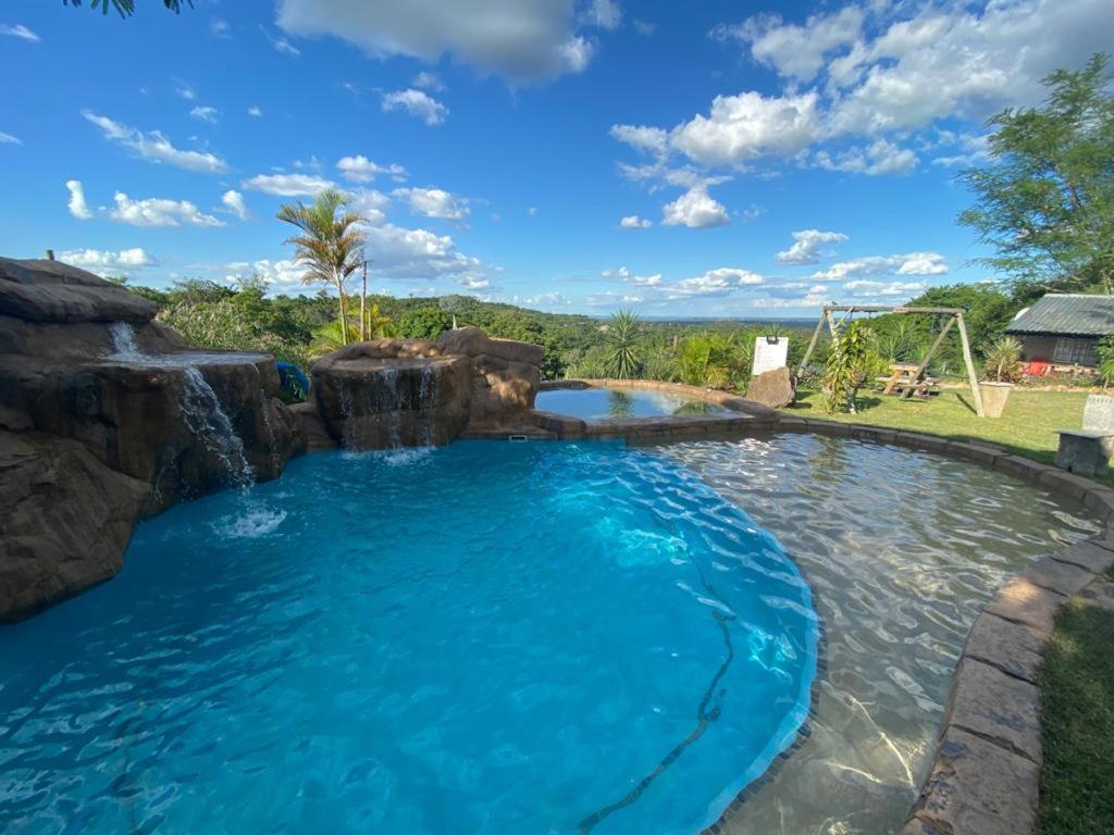 a large swimming pool with a waterfall and a slide at Numbi Hills Self-Catering in Hazyview
